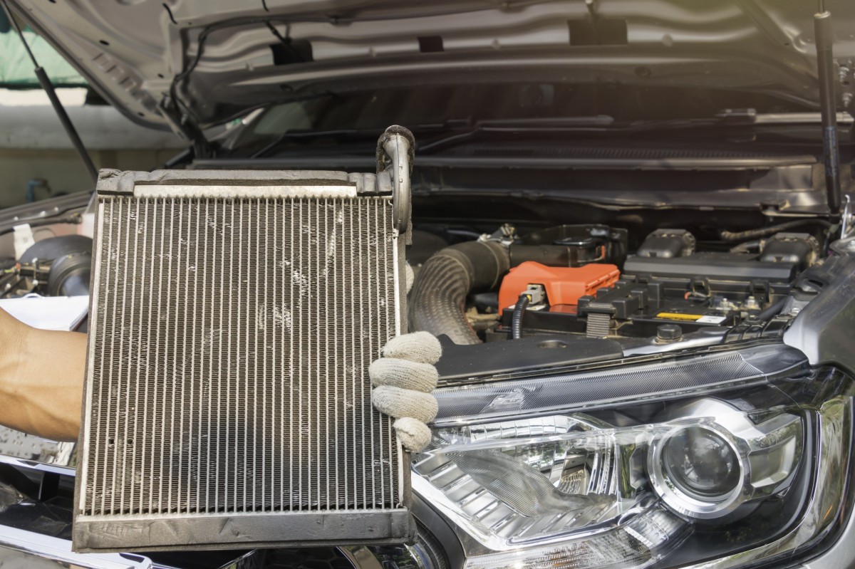 hand holding radiator in front of car with hood up 