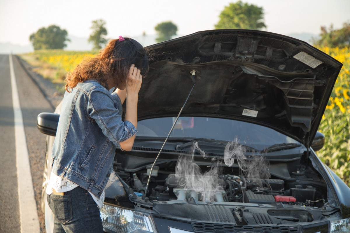 Woman checking out under the hood where steam is coming from